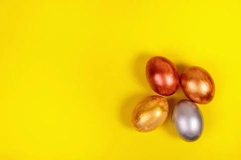 Multi-colored eggs on a uniform yellow background with place for text. Stock Photos