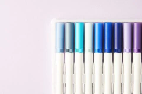Multi colored felt-tip pens with blue spectrum in the corner of the paper sheet Stock Photos
