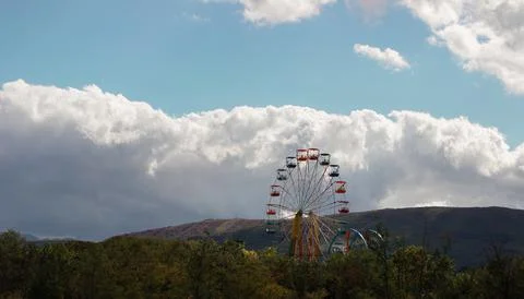 Multi-colored Ferris wheel in the mountains against the background of the sky Stock Photos