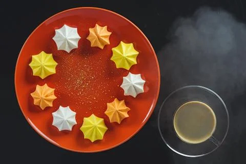 Multi-colored figured cookies on a round orange plate and a cup of hot coffee on Stock Photos