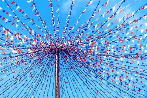 Multi-colored flags and light bulbs on a pole against a blue sky Foto stock