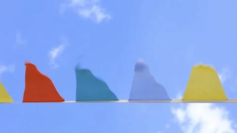 Multi-colored flags on rope against blue sky with clouds Stock Footage 169334932