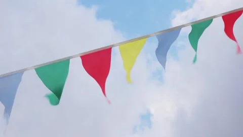 Multi-colored flags on rope against blue sky with clouds Stock Footage 169334939