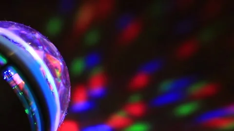 A multi-colored flashlight glows in different colors in the dark on the wall. Video stock 132067611