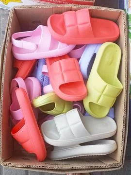 Multi-colored flip-flops are mixed in a box Stock Photos