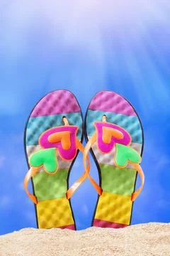 Multi colored flip flops, slates with heart on sand. Sunny day Stock Photos
