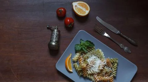 Multi-colored fusilli on a gray rectangular plate on a dark table with a pepper Stock Photos