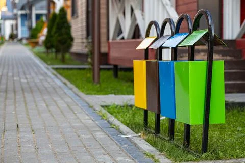 Multi-colored garbage containers line the path on the street Stock Photos