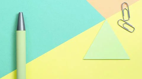 Multi colored geometric background with Green pen and paper clips. Stock-Fotos