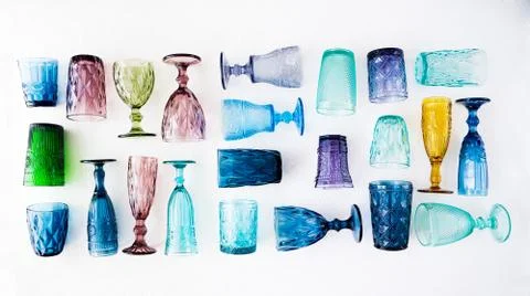 Multi-colored glass empty wine glasses and glasses lie on a white background. Stock Photos