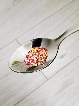 Multi-Colored granules in a spoon on an isolated background Stock Photos