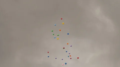 Multi-colored inflatable balls fly against a cloudy sky background Stock Footage 90886827