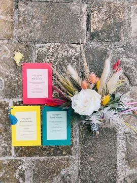 Multi-colored invitations lie on the paving stones next to the wedding bouquet 스톡 사진