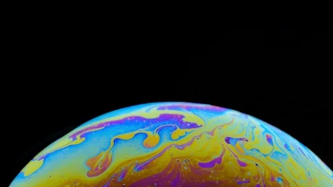 Multi-colored iris of a soap bubble in motion. black background. Stock Footage 114710573