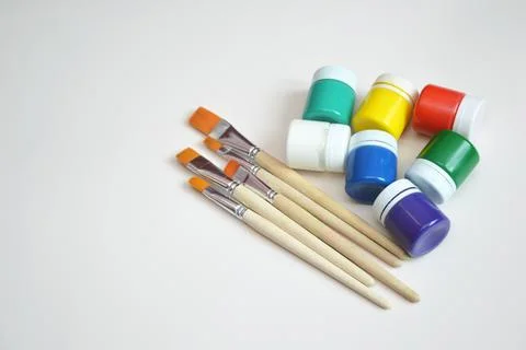 Multi-colored jars of gouache paint and synthetic brushes. A set of objects f Stock Photos