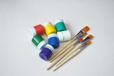 Multi-colored jars of gouache paint and synthetic brushes. A set of objects f Stock Photos
