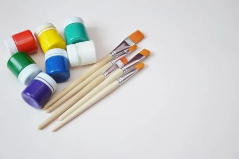 Multi-colored jars of gouache paint and synthetic brushes. A set of objects f Foto stock