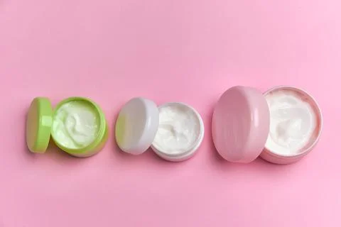 Multi-colored jars with white cosmetic cream for face Stock Photos