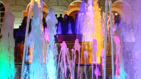 Multi-colored jets of a fountain, in the background tourists in defocus Stock Footage 119664992