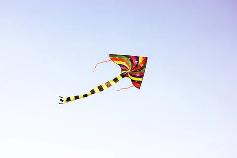 A multi-colored kite flies high in a sky. Children's entertainment, outdoor fun Stock Photos
