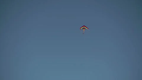 A multi-colored kite flying high in the blue sky under the gusts of wind. Stock Footage 196625583