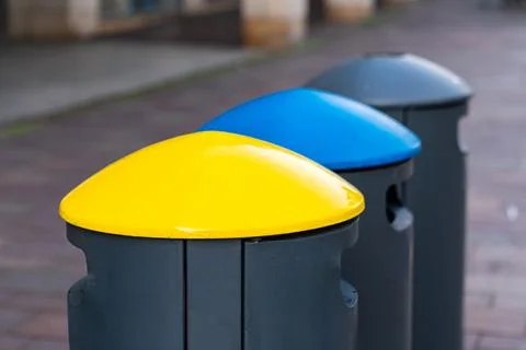 Multi-colored lids of garbage cans in the pedestrian zone of the city. Stock Photos