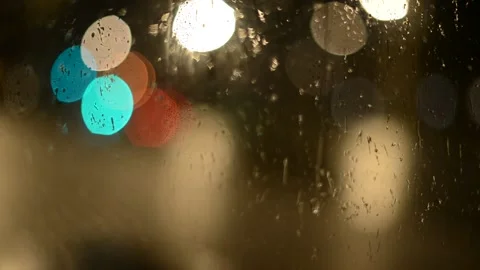 Multi-colored lights of night traffic and city lighting through a rain-splat Stock Footage 237098308