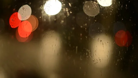Multi-colored lights of night traffic and city lighting through a rain-splat Stock Footage 237098364