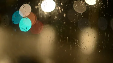 Multi-colored lights of night traffic and city lighting through a rain-splat Stock Footage 237098412