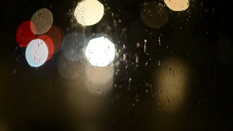 Multi-colored lights of night traffic and city lighting through a rain-splat Stock Footage 237098430