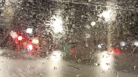 Multi-colored lights of night traffic and city lighting through a rain-splat Stock Footage 237099027