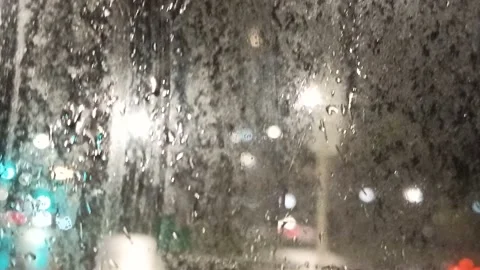 Multi-colored lights of night traffic and city lighting through a rain-splat Stock Footage 237099049