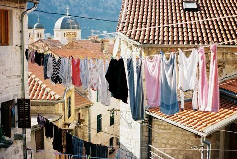 Multi-colored linen hangs on ropes between old houses. Kotor, Montenegro Stock Photos