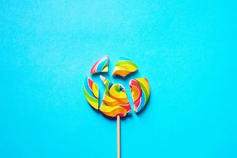 Multi-colored lollipop is divided into several parts. On a blue background Stock Photos