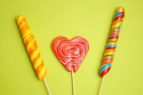 Multi-colored lollipops of different shapes on a green background. Stock Photos