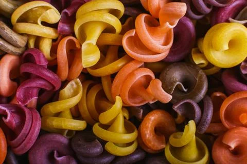 Multi-colored macaroni of an unusual form with natural vegetable dyes. Backgr Stock Photos