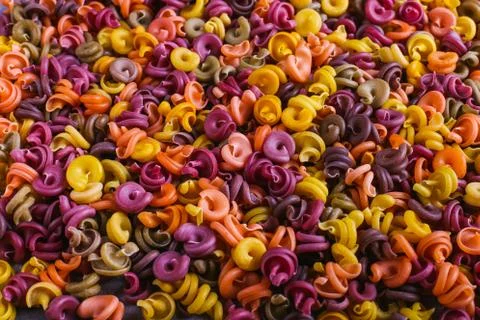 Multi-colored macaroni of an unusual form with natural vegetable dyes. Backgr Stock Photos