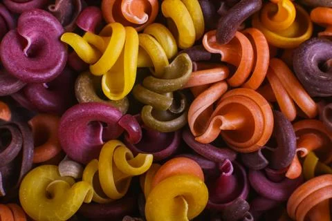 Multi-colored macaroni of an unusual form with natural vegetable dyes. Backgr Stock Photos