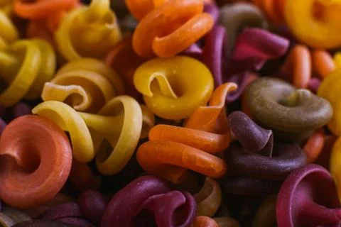 Multi-colored macaroni of an unusual form with natural vegetable dyes. Backgr Stock Photos