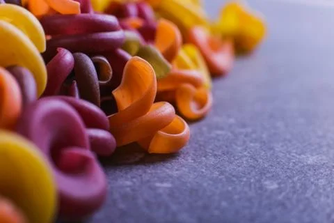 Multi-colored macaroni of an unusual form with natural vegetable dyes. Backgr Stock Photos