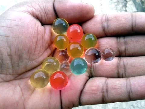 Multi colored marbel in a hand Stock Photos