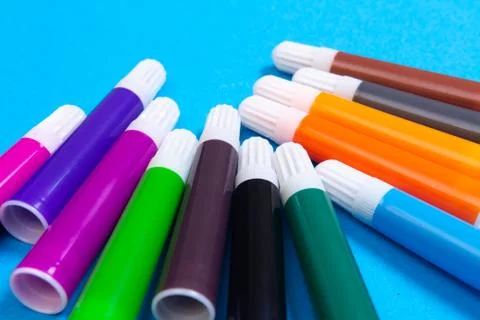 Multi colored markers on blue background Stock Photos