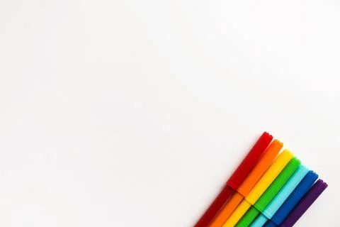 Multi-colored markers lie on a white background in a rainbow order in the lower Stock Photos