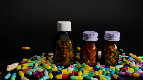 Multi-colored medicine capsules and bottles on a rotating stand. Stock Footage 252485090