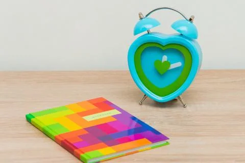 Multi-colored notebook on a wooden background with a clock Fotos Stock