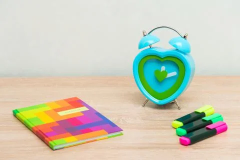 Multi-colored notebook on a wooden background with a clock Foto stock