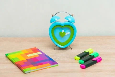 Multi-colored notebook on a wooden background with a clock Stock Photos