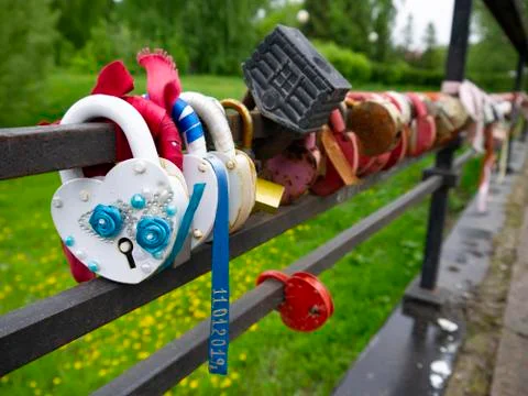 Multi-colored padlocks with keys thrown into the river. Symbols of fidelity a Stock Photos