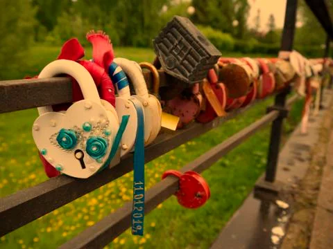 Multi-colored padlocks with keys thrown into the river. Symbols of fidelity a Stock Photos