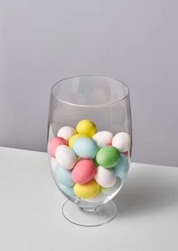 Multi-colored painted eggs in a glass vase on a gray background with space for 스톡 사진